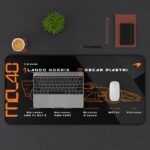 Black MCL40 technical spec desk mat with Lando Norris and Oscar Piastri details and papaya orange blueprint