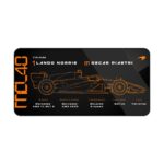 Black MCL40 technical spec desk mat with Lando Norris and Oscar Piastri details and papaya orange blueprint